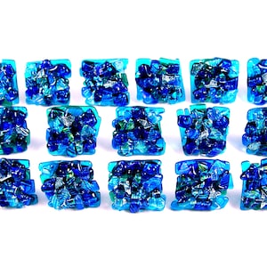 May include: A set of 16 blue and green glass mosaic tiles. Each tile is square shaped and features a unique pattern of blue and green glass pieces.