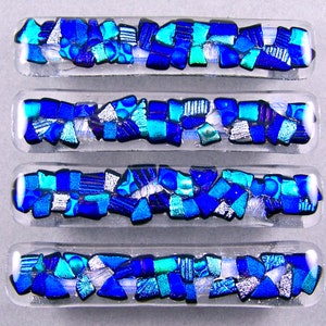 May include: Four glass tiles with a mosaic design of blue, turquoise, and silver pieces. The tiles are rectangular and have a clear glass background.