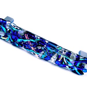 May include: A blue and iridescent glass cabinet pull with a silver metal mounting plate.