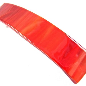 May include: A red glass hair clip with a marbled effect.