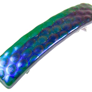 May include: A rectangular hair barrette with a textured surface. The barrette features a color gradient of green, blue, and purple. The barrette is made of a shiny material and has a silver clasp on the back. Hair accessory.