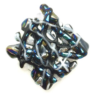 May include: A black and white glass art piece with iridescent accents. The piece is made of multiple layers of glass that have been fused together. The glass is clear, black, and white, with iridescent accents. The piece is abstract in design and has a modern look.