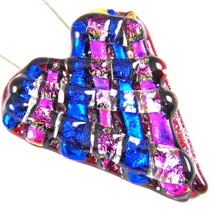 May include: A dichroic glass heart pendant with a silver chain. The pendant features a mosaic of vibrant colors, including blue, pink, and silver, set against a black background. The heart shape is slightly asymmetrical, adding a unique touch to the jewelry.