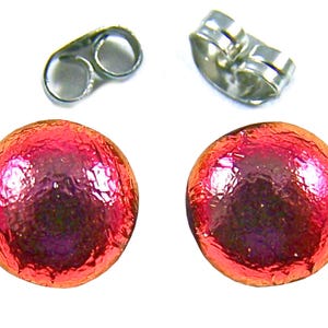 May include: A pair of round, red stud earrings with a textured surface. The earrings are accompanied by two silver-colored earring backs. The earrings are a simple, yet elegant accessory.
