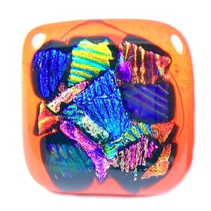 May include: A square, orange glass pendant with a dichroic glass design. The dichroic glass features vibrant colors including blue, purple, yellow, and red. The pendant has rounded corners and a glossy finish.