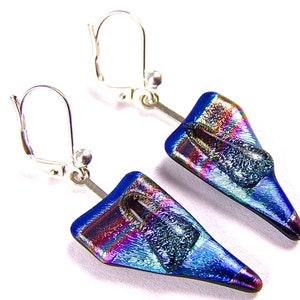 May include: Dichroic glass earrings with an iridescent finish. The earrings have a triangular shape with a deep blue base and accents of purple, green, and silver. They are suspended from silver-coloured lever-back ear wires. The earrings are approximately 3 cm in length.