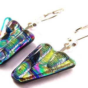 May include: A pair of dichroic glass earrings with an iridescent finish. The earrings have a triangular shape with a black base and silver lever-back closures. The colours shift from green to blue and purple.