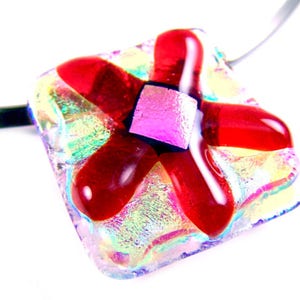May include: A dichroic glass pendant necklace with a square shape and a red flower design. The pendant has iridescent colours and is attached to a silver-tone necklace.