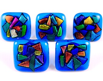 May include: Five square-shaped glass knobs with a blue background and colorful mosaic designs. The mosaic pieces are made of glass and have a metallic sheen.