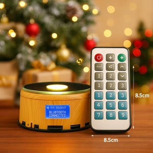 May include: A wooden-effect speaker with a blue display showing "BLUBTOOTH CONNECTED" and a timer. A remote control (8.5cm) with buttons is next to the speaker. The speaker is on a wooden surface, with a Christmas tree in the background.
