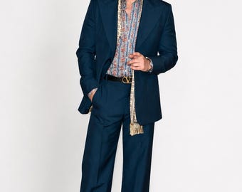 Traje de hombre azul verdoso oscuro, estilo años 70, de pierna ancha y corte relajado.