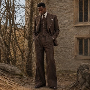 May include: A dark brown three-piece suit consisting of a double-breasted blazer, a button-up vest, and wide-leg trousers. The ensemble includes a light-colored collared shirt, a dark necktie, and a small silver-toned pin on the blazer lapel.