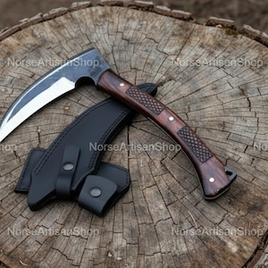 Puede incluir: Un cuchillo de hoja curva con mango de madera oscura y funda de cuero negro, apoyado sobre un tocón de árbol desgastado. La hoja es plateada y el mango es de color marrón oscuro. La funda tiene un cierre a presión.