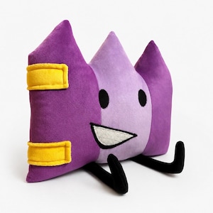 May include: A plush toy in the shape of a smiling, cartoon-like character. The toy is primarily purple and lavender, with black eyes and legs, and yellow accents. The character has a white, triangular mouth.