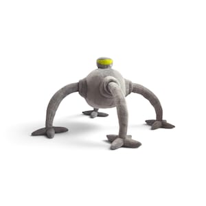 May include: A plush toy shaped like a gray robot with a spherical body, four segmented legs ending in star-shaped feet, and a small head featuring a single horizontal yellow visor. The soft fabric construction gives the creature a rounded form.