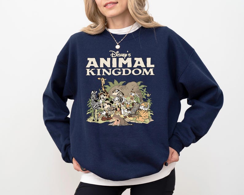 May include: A navy blue crew neck sweatshirt with the text "Disney's Animal Kingdom" in cream. The graphic depicts cartoon animals including a zebra, giraffe, and tiger. The sweatshirt is a casual style.