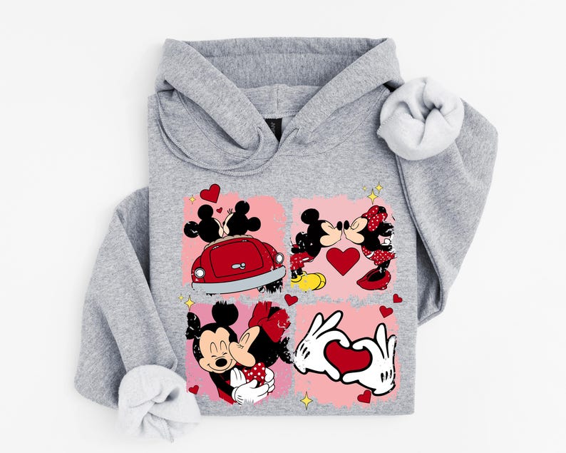 May include: A grey hoodie with a vibrant graphic of Mickey and Minnie Mouse in romantic scenes. The design incorporates hearts, a red car, and the characters kissing. A comfortable and playful design.