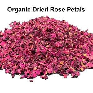 Op de afbeelding: Een hoop biologische gedroogde rozenblaadjes in roze en bordeaux tinten. De bloemblaadjes hebben een zichtbare textuur. De tekst "Organic Dried Rose Petals" staat bovenaan de afbeelding.