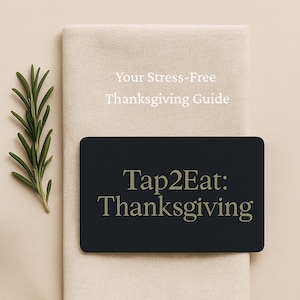 Può includere: Una carta rettangolare nera con il testo Tap2Eat: Thanksgiving in lettere dorate, posizionata su un tovagliolo di stoffa beige con un rametto di rosmarino verde. Sopra la carta, il testo Your Stress-Free Thanksgiving Guide è stampato in bianco.