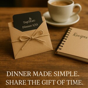 Pu&ograve; includere: Una carta rettangolare nera con il testo Tap2Eat: Dinner 5/15 all'interno di una busta di carta marrone legata con un fiocco di spago di juta. Accanto si trovano un taccuino a spirale con la parola Recipes sulla copertina e una tazza da caff&egrave;.