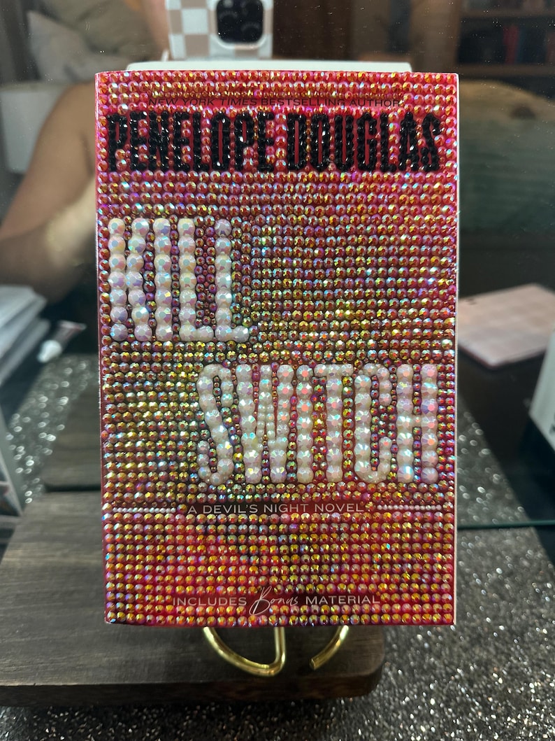 Pu&ograve; includere: Una copertina di libro rettangolare ricoperta di piccole, scintillanti, strass iridescenti. Il titolo "KILL SWITCH" &egrave; in grandi lettere bianche. Il nome dell'autore, "PENELOPE DOUGLAS", &egrave; in alto in lettere nere.