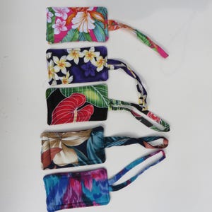 Peut inclure: Cinq &eacute;tiquettes de bagages avec des motifs floraux color&eacute;s. Chaque &eacute;tiquette a une forme rectangulaire avec une boucle en tissu assortie. Les motifs comprennent des fleurs roses et blanches, des fleurs jaunes et violettes, des feuilles rouges et des motifs abstraits.