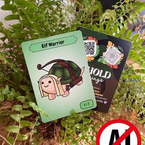 May include: Two trading cards featuring fantasy art. One card has an elf warrior with a turtle shell, the text "Elf Warrior", and "1/1". The other card has a camouflage background with QR codes and the text "HOLD ings". The cards are set against a backdrop of green foliage.