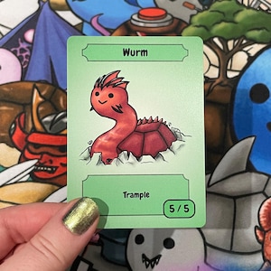 May include: A green card with a cartoon worm illustration. The card is labelled "Worm" at the top and "Trample" below the image. The card also shows "5/5" in a small circle. The worm is red with a spiky back.