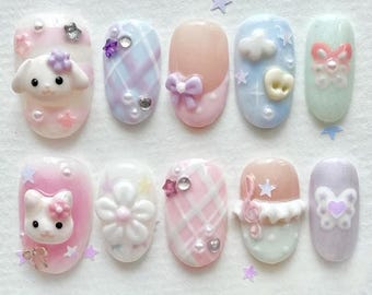 May include: A set of ten pastel-colored press-on nails with various designs. Each nail features 3D embellishments like bows, flowers, and cartoon characters. The color palette includes pink, blue, and lavender, with glitter and pearl accents. The nails are oval-shaped.
