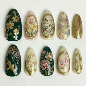 May include: A collection of ten almond-shaped artificial nails with intricate floral and nature-inspired designs. The nails feature gold accents and a variety of colors, including green, pink, and cream. Designs include flowers, birds, and butterflies.