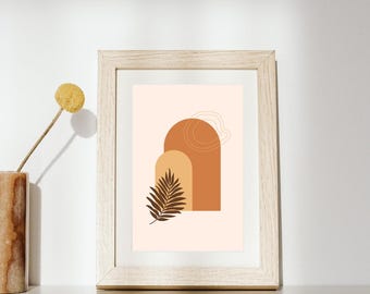 Puede incluir: Un marco de madera clara que contiene una impresión con fondo pálido, dos formas de arco superpuestas en tonos naranja y bronceado, y una ilustración de hoja de palma marrón oscuro. Un dibujo de línea fina y clara se sitúa sobre los arcos.