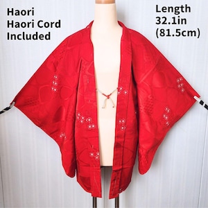 May include: A vibrant red Haori jacket with a length of 32.1 inches (81.5cm). The jacket features a subtle floral pattern and is accompanied by a Haori cord. The garment is displayed on a mannequin, showcasing its open-front design.