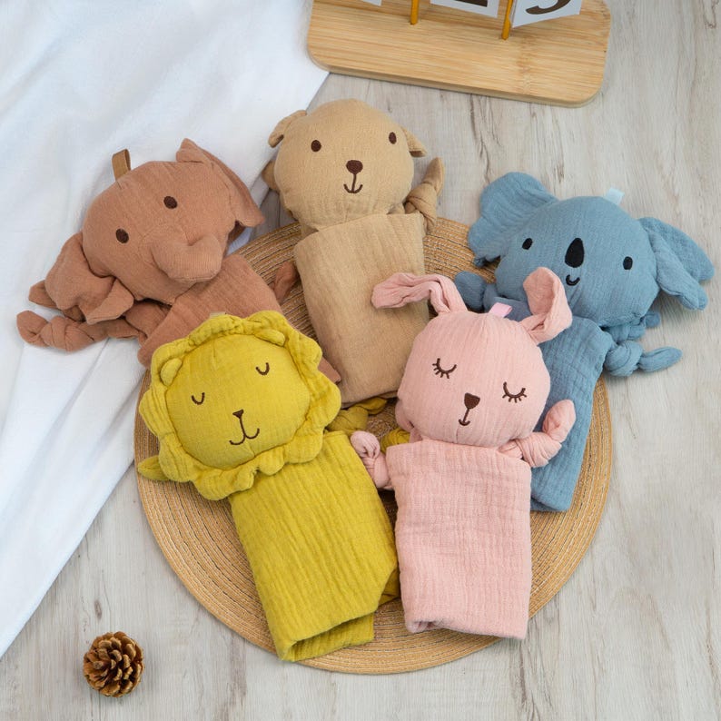 Pu&ograve; includere: Una collezione di morbidi burattini a forma di animali in vari colori. I burattini includono un elefante, un orso, un koala, un leone e un coniglio. Ogni burattino ha tratti del viso ricamati ed &egrave; realizzato in un tessuto strutturato. I burattini sono disposti su un tappetino intrecciato.
