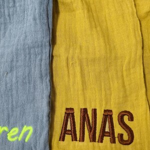 Pu&ograve; includere: Primo piano di tre sezioni di tessuto in blu, giallo e giallo-verde. La sezione gialla ha la parola ricamata "ANAS" in marrone. La sezione blu ha la parola ricamata "Iperen" in verde neon. La sezione giallo-verde ha la parola ricamata "BI" in nero.