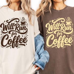 Puede incluir: Dos camisetas, una crema y otra marrón, con la frase "Will Run for Coffee" en una tipografía decorativa. El diseño incluye una taza de café y estrellas, ideal para los amantes del café.