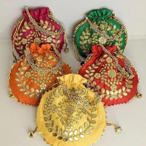May include: A collection of five colorful, round drawstring pouches. Each pouch is a different color: fuchsia, green, orange, red, and yellow. They are adorned with gold embroidery and beaded accents, with a drawstring closure.