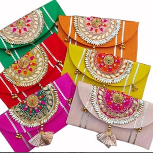 Puede incluir: Una colección de coloridos bolsos de mano adornados. Cada bolso presenta un cierre de solapa, bordados decorativos y una borla. Los colores incluyen verde, naranja, rojo, amarillo, rosa y rosa claro. Rayas plateadas verticales y detalles dorados añaden detalles.