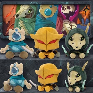 May include: A collection of six plush toys featuring three distinct character designs. The figures include a blue creature with a single eye, a yellow armored character with red eyes, and a green hooded creature with horns, displayed in two rows.