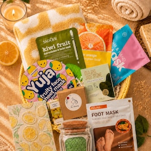 Pode incluir: Uma coleção de produtos de cuidados com a pele, incluindo uma máscara de kiwi Sadoer, uma máscara facial frutada Yuja, uma pedra de jade Gua Sha, uma máscara para pés Melao, uma caixa castanha, um frasco com sais de banho verdes e um cartão.