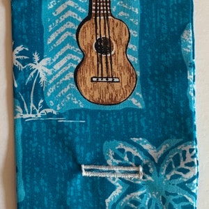 May include: A blue fabric pouch with a white ukulele and palm tree design. The pouch has white stitching and a white button.