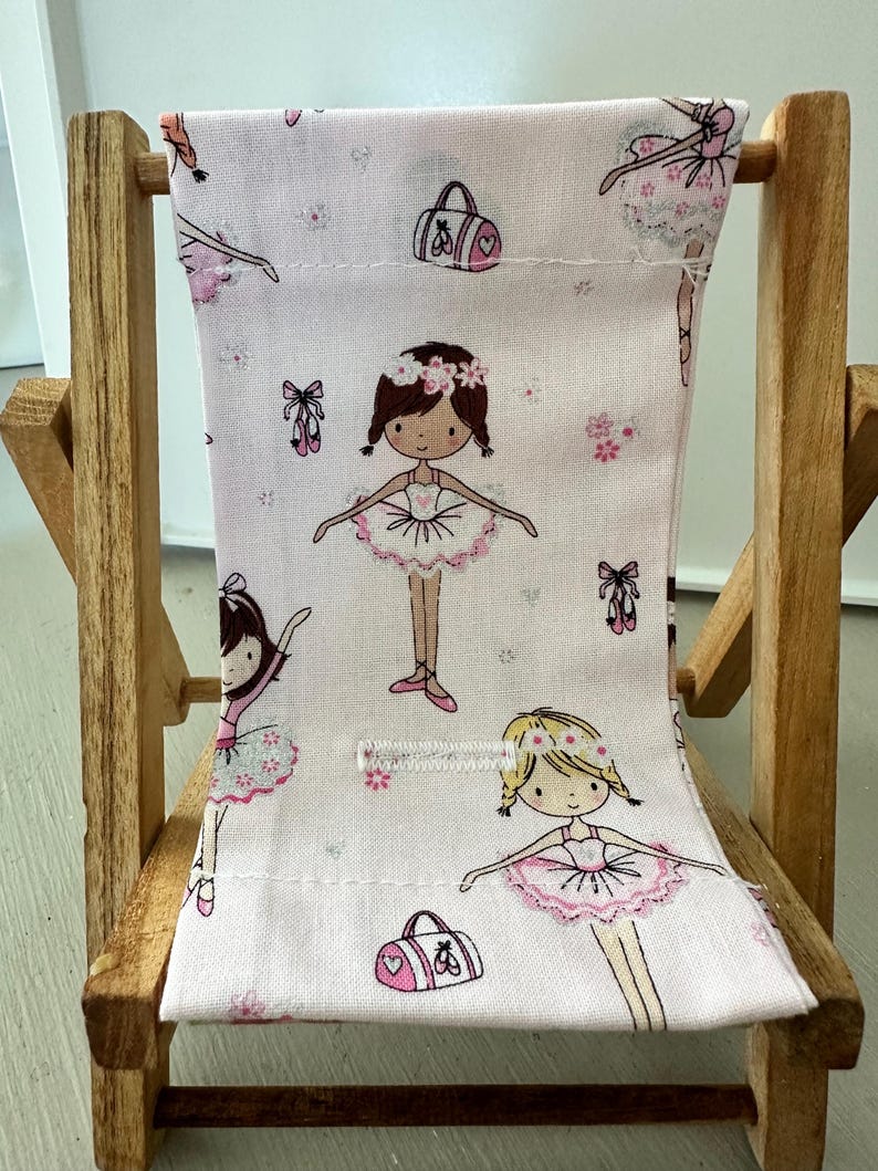 Puede incluir: Una peque&ntilde;a silla de madera con un asiento de tela rosa con un patr&oacute;n de bailarinas, flores y bolsas de ballet. La silla es perfecta para una casa de mu&ntilde;ecas o una sala de juegos.