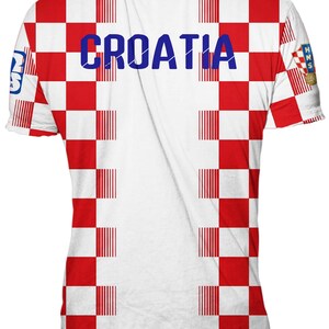 May include: A short-sleeve t-shirt featuring a red and white checkered pattern across the front and back. The word CROATIA is printed in blue across the chest. A small HNS logo with a soccer ball is visible on the right sleeve, and a logo on the left.
