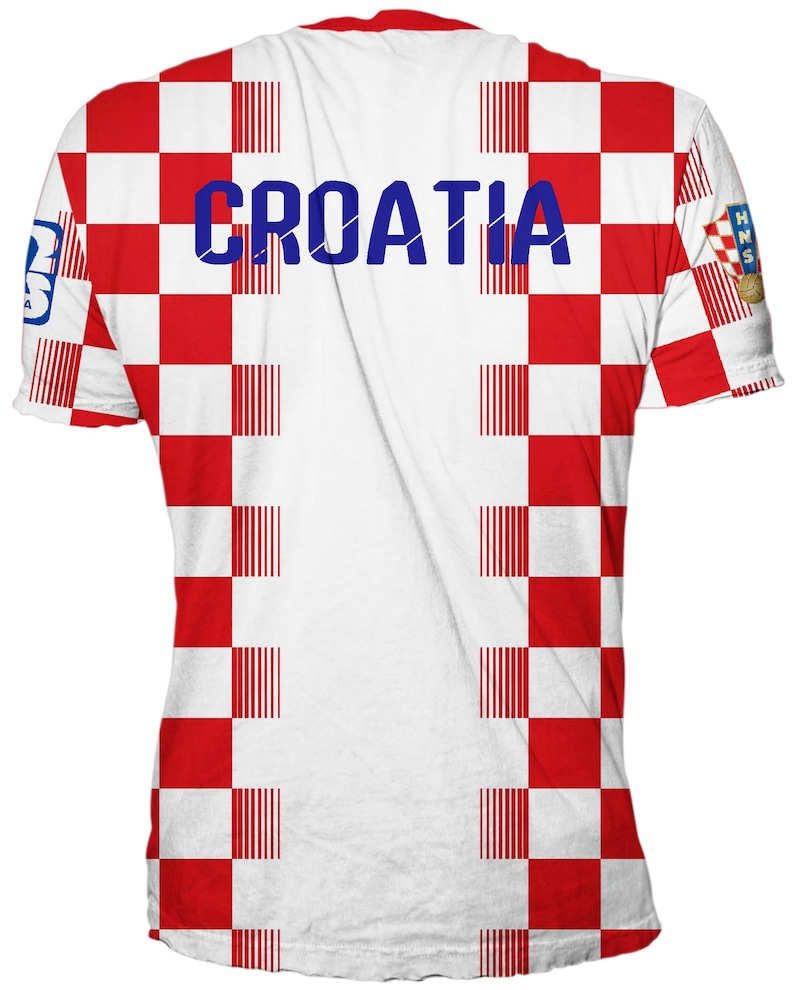 May include: A short-sleeve t-shirt featuring a red and white checkered pattern across the front and back. The word CROATIA is printed in blue across the chest. A small HNS logo with a soccer ball is visible on the right sleeve, and a logo on the left.