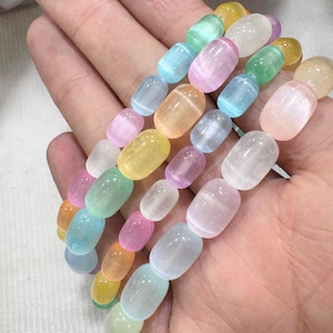 May include: A collection of colorful gemstone bead bracelets. The beads are oval-shaped and come in a variety of pastel colors, including pink, blue, yellow, and green. The bracelets are strung together, showcasing the natural variations in the stones.