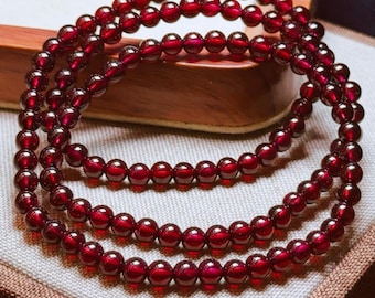 May include: Three strands of deep red, polished gemstone beads. The beads are round and uniform in size, strung together to form necklaces or bracelets. The jewelry is displayed on a neutral surface.