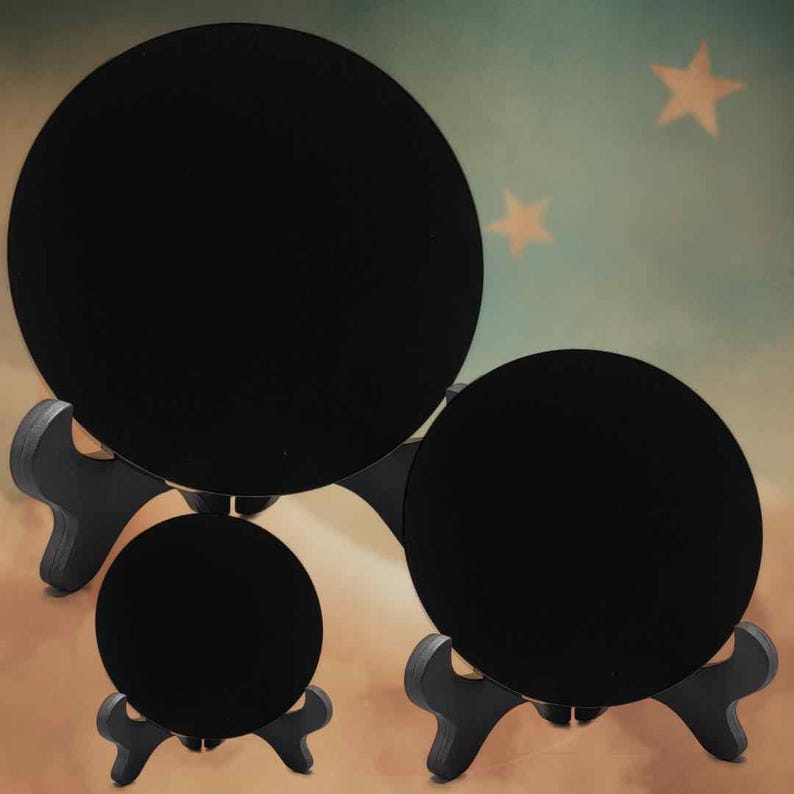 May include: Three black, circular display stands of different sizes. Each stand supports a round object, forming a tiered arrangement. The stands are crafted from dark wood, designed for displaying items. The background has a soft gradient with star shapes.