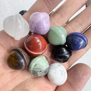 May include: A collection of polished gemstones in various colors, including white, purple, red, green, blue, black, brown, and gray. The stones have rounded shapes and smooth surfaces, showcasing natural patterns and textures. These gemstones are ideal for jewelry making or collecting.