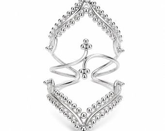 Puede incluir: Un anillo de plata para todo el dedo con dos bandas en forma de cheurón adornadas con pequeñas cuentas esféricas. Las dos secciones están conectadas por una barra vertical central que termina en un pequeño grupo de tres cuentas arriba y abajo.