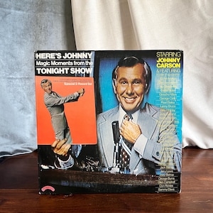 May include: A vintage vinyl record album titled "Here's Johnny: Magic Moments from the Tonight Show." The album cover features a smiling Johnny Carson and a smaller image of him. The album is a special 2-record set.