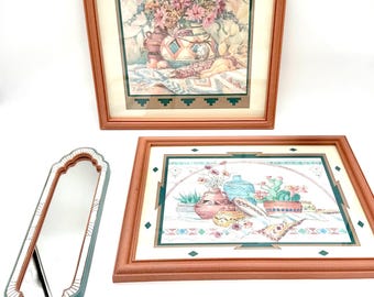 May include: Two framed floral prints and two decorative mirrors. The prints feature still life arrangements of flowers and pottery in a Southwestern style. The mirrors have a teal and white trim.